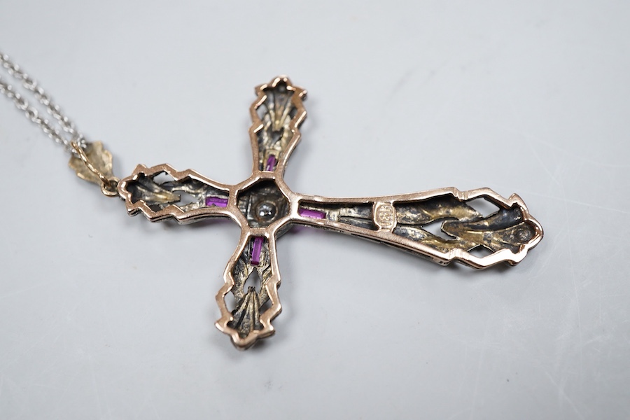 A synthetic ruby and diamond pendant, designed as a foliate cross, set with a brilliant-cut diamonds and step-cut synthetic rubies, on a chain necklace, mounted in gold, pendant length 5.4cm, stamped 18K, necklace length